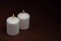 Two whiteÃÂ candlesÃÂ flameÃÂ burningÃÂ onÃÂ dark backgroundÃÂ withÃÂ copyÃÂ space forÃÂ text Royalty Free Stock Photo